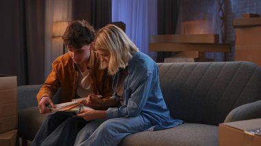 Genç bir adam ve bir kadın oturma odasında bir taşınma partisi hakkında konuşuyorlar. Birbirine aşık bir çift bir koltukta oturup gelecekteki ev tasarımları hakkında konuşuyorlar..