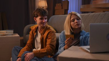 Genç bir adam ve bir kadın oturma odasında bir taşınma partisi hakkında konuşuyorlar. Birbirine aşık bir çift yerde oturuyor, kız ödeme kartı detaylarını bir dizüstü bilgisayara başarıyla giriyor..