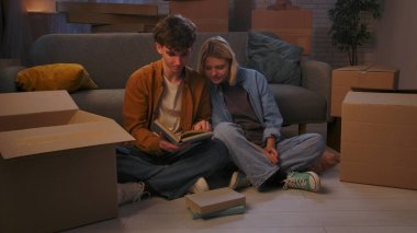 Genç bir adam ve bir kadın oturma odasında bir taşınma partisi hakkında konuşuyorlar. Birbirine aşık bir çift yerde oturuyor, adam en sevdiği kitapları kutulardan çıkarıyor..