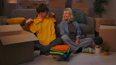 Genç bir adam ve bir kadın oturma odasında bir taşınma partisi hakkında konuşuyorlar. Birbirine aşık bir çift yerde oturuyordu. Adam en sevdiği tişörtleri kutulardan çıkardı..