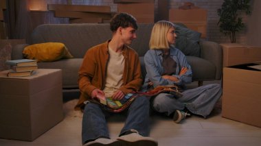 Genç bir adam ve bir kadın oturma odasında bir taşınma partisi hakkında konuşuyorlar. Birbirine aşık bir çift yere oturur ve evleri için yeni bir tasarım hakkında konuşur..
