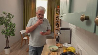 Son sınıf öğrencisinin hayatında bir gün. Yaşlı gri saçlı adam sabah mutfakta, akıllı telefondan mesaj atan adam, uygulamayla mesaj yollayan, günlük yaşam tarzı konsepti.