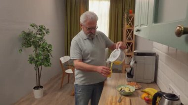 Son sınıf öğrencisinin hayatında bir gün. Yaşlı gri saçlı adam sabah mutfakta kahvaltı hazırlıyor, portakal suyu bardakta ve kahve makinesinden kahve bekliyor. Günlük rutin yaşam tarzı kavramı.