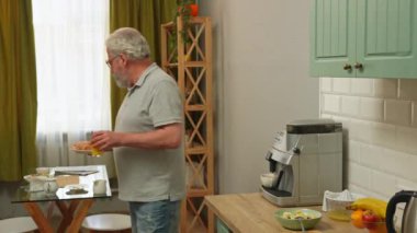 Son sınıf öğrencisinin hayatında bir gün. Yaşlı gri saçlı adam, sabah mutfakta, içkileri alır ve ekmek ve yulaf ile bowling oynar, sağlıklı kahvaltısını masaya koyar. Günlük rutin yaşam tarzı kavramı.