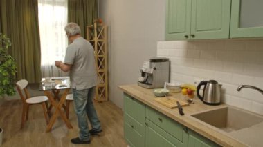 Son sınıf öğrencisinin hayatında bir gün. Yaşlı gri saçlı adam, sabah mutfakta, içkileri alır ve ekmek ve yulaf ile bowling oynar, sağlıklı kahvaltısını masaya koyar. Günlük rutin yaşam tarzı kavramı.