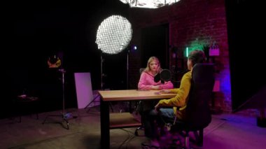 Çevrimiçi yayın. Erkek sunucu ve kadın konuk kayıt stüdyosunda mikrofon kullanarak dijital içerik yaratarak yapılan röportajın sahne arkası görüntüsü..