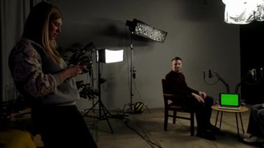 Çevrimiçi podcast gösterisi. Sahne arkası sunucusu ve konuk kayıt stüdyosunda dijital içerik yaratma, yapımcı sunucu ve kadınla konuşma, masadaki dizüstü kroma anahtar yeşil ekran.