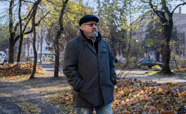 День в жизни пожилого человека. Утром на улице пожилой седой мужчина, наслаждающийся утренней прогулкой по городу, гуляющий по улице и оглядывающийся. Концепция повседневного образа жизни.