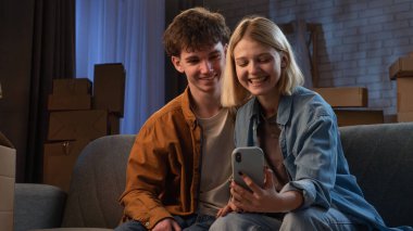 Genç bir adam ve bir kadın oturma odasında bir taşınma partisi hakkında konuşuyorlar. Birbirine aşık bir çift bir kanepede oturmuş yeni evlerini gösteriyorlar..