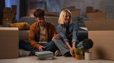 Genç bir adam ve bir kadın oturma odasında bir taşınma partisi hakkında konuşuyorlar. Birbirine aşık bir çift yerde oturuyor. Kız, evi sıcak tutmak için kutudan dekorasyon malzemelerini çıkarıyor..