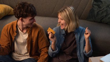 Genç bir adam ve bir kadın oturma odasında bir taşınma partisi hakkında konuşuyorlar. Birbirine aşık bir çift yerde oturuyor, kız ödeme kartı detaylarını bir dizüstü bilgisayara başarıyla giriyor..