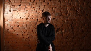Siyah elbiseli genç adam kırmızı tuğla duvara karşı hip hop dansı yapıyor..