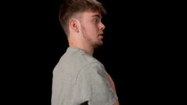 Açık gri elbiseli genç adam siyah arka planda hip-hop yapıyor..