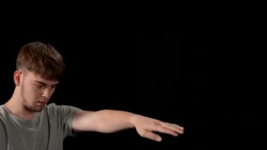 Açık gri elbiseli genç adam siyah arka planda hip-hop yapıyor..