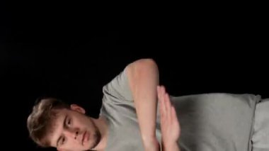 Açık gri elbiseli genç adam siyah arka planda hip-hop yapıyor..