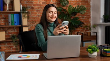 Ofiste çalışan bir iş adamı. Genç iş kadını geç saatlere kadar ofis dairesinde çalışıyor, dizüstü bilgisayar kullanıyor, akıllı telefondan mesaj atıyor, mesajlar yolluyor, gülümsüyor..