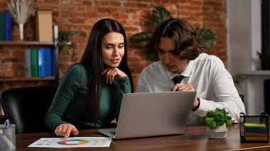 Ofiste çalışan bir iş adamı. İş kadını, iş arkadaşıyla aynı masada oturuyor, geç saatlere kadar ofiste çalışıyor, dizüstü bilgisayar kullanıyor, belgeleri okuyor, bilgi hakkında konuşuyor..
