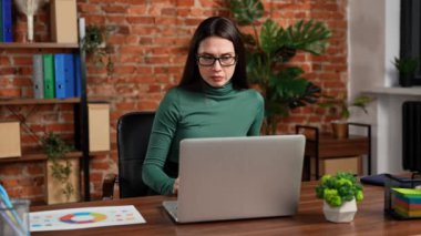 Ofiste çalışan bir iş adamı. Genç iş kadını geç saatlere kadar ofis dairesinde çalışıyor, dizüstü bilgisayar kullanıyor, ekranda belge okuyor, hatalar buluyor, şaşırmış olumsuz ifade.