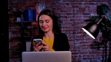 Ofiste çalışan bir iş adamı. Genç iş kadını geç saatlere kadar ofis dairesinde çalışıyor, kişisel pov, akıllı telefondan mesaj yolluyor, gülümseyen yüz ifadesi takınıyor..