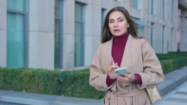 Günlük rutin yaşam tarzı konsepti. Sabahları genç esmer bir kadın işe gitmek için sabah yürüyüşünden zevk alıyor. Sokakta yürüyor, etrafa bakıyor, akıllı telefondan mesaj atıyor..