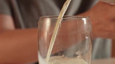 Günlük ev yemeği rutini. Evdeki masada oturan kadın waffle kahvaltısı için hamur hazırlıyor, bardağa süt döken kadını yakından çekiyor. Yavaş çekim.