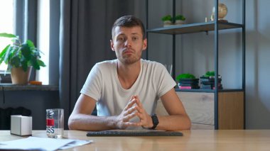 Çevrimiçi kursa katılan kişi. Üniversitede okuyan erkek öğrenci, masa başında oturur, bilgisayarda ders izler, kameraya bakar, konsantre yüzlüdür. Modern online eğitim.