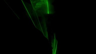 Profesyonel yıldırım teknolojisi konsepti. Parıldayan yeşil lazer ışını karanlıkta yanıp sönüyor, dumanlı havada parlayan renkli ışık projektörü, siyah arka planda izole edilmiş..