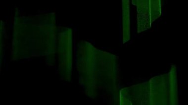 Profesyonel yıldırım teknolojisi konsepti. Parıldayan yeşil lazer ışını karanlıkta yanıp sönüyor, dumanlı havada parlayan renkli ışık projektörü, siyah arka planda izole edilmiş..