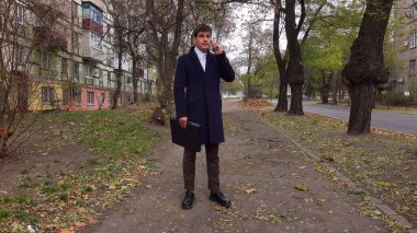 Günlük rutin yaşam tarzı konsepti. Sabahları genç işadamı şehirdeki ofisine günlük yürüyüşünün tadını çıkarıyor. Evrak çantasıyla sokakta yürüyor ve akıllı telefondan konuşuyor..