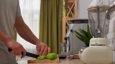 Günlük rutin yaşam tarzı konsepti. Genç adam sabah mutfakta sağlıklı bir kahvaltı hazırlıyor, taze meyve püresi yapıyor, kivi kesiyor ve blender koyuyor..