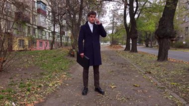 Günlük rutin yaşam tarzı konsepti. Sabahları genç işadamı şehirdeki ofisine günlük yürüyüşünün keyfini çıkarıyor. Elinde evrak çantasıyla caddede duruyor ve akıllı telefonuyla konuşuyor..