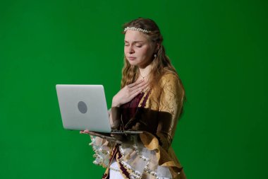 Tarihsel reklam konsepti. Krom anahtar yeşil ekran arka planda antik kıyafetli bir kadın. Rönesans elbisesi giymiş üzgün yüzlü ve elinde dizüstü bilgisayarla ekrana bakan bir kadın..