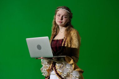 Tarihsel reklam konsepti. Krom anahtar yeşil ekran arka planda antik kıyafetli bir kadın. Rönesans kıyafetli, üzgün yüzlü dizüstü bilgisayarı olan ve kameraya bakan bir kadın..