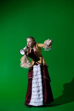 Tarihsel reklam konsepti. Krom anahtar yeşil ekran arka planda antik kıyafetli bir kadın. Rönesans elbisesi giymiş, kızgın yüzüyle megafonla bağıran bir kadın..