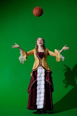 Tarihsel reklam konsepti. Krom anahtar yeşil ekran arka planda antik kıyafetli bir kadın. Rönesans elbisesi giymiş, elleri açık, yukarıdan düşen basketbol topuna bakan bir kadın..