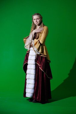 Tarihsel reklam konsepti. Krom anahtar yeşil ekran arka planda antik kıyafetli bir kadın. Rönesans elbisesi giymiş, negatif tiksindirici yüzü olan kameraya bakıp poz veren bir kadın..