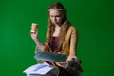 Tarihsel reklam konsepti. Krom anahtar yeşil ekran arka planda antik kıyafetli bir kadın. Rönesans elbisesi giymiş bir kadın oturmuş kağıt belgeler okuyor ve elinde kahve fincanı tutuyor..