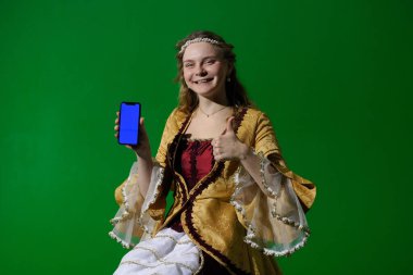 Tarihsel reklam konsepti. Krom anahtar yeşil ekran arka planda antik kıyafetli bir kadın. Rönesans elbisesi giymiş bir kadın elinde mavi reklam ekranlı akıllı bir telefonla oturuyor..