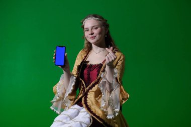 Tarihsel reklam konsepti. Krom anahtar yeşil ekran arka planda antik kıyafetli bir kadın. Rönesans elbisesi giymiş bir kadın elinde mavi reklam ekranlı akıllı bir telefonla oturuyor..