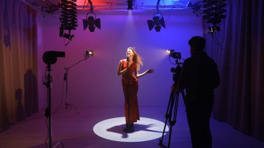 Profesyonel bir stüdyonun içinde. Işıklandırma ekipmanları ve siklonamayla fotoğraf çekimi stüdyoları, sahne arkasında neon ışıklı retro mikrofonla şarkı söyleyen kadın şarkıcılar..