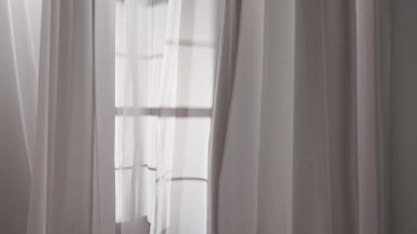 Rüzgarın savurduğu renkli tül kumaşlı pencereler. Açık bir pencereden süzülen şeffaf beyaz ipek perdeler, pencere çerçevesinden yansıyan gölgeler tekstil üzerine yansıyor.