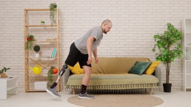 Konforlu bir oturma odasında protez bacaklı bir adam yerde yatarak tahta egzersizi yapıyor, rehabilitasyon, sağlıklı yaşam. Kısıtlı hareketli adaptif yaşam kavramı.