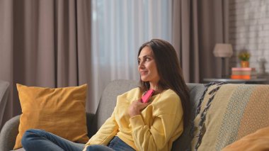 Kadın evde boş vakit geçiriyor. Genç bir kadın bütün gününü evinde, oturma odasındaki kanepede oturarak geçiriyor. Elinde akıllı telefon, mutlu bir ifade var..