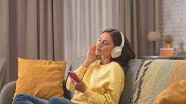 Kadın evde boş vakit geçiriyor. Genç bir kadın bütün gününü evde, oturma odasındaki kanepede oturarak, kulaklık takarak, akıllı telefondan dinlenerek, sakin bir ifadeyle, dinlenerek geçirir..