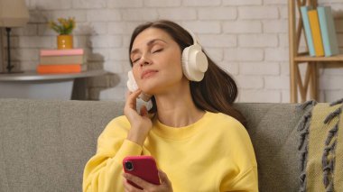 Kadın evde boş vakit geçiriyor. Genç bir kadın bütün gününü evde, oturma odasındaki kanepede oturarak, kulaklık takarak, akıllı telefondan dinlenerek, sakin bir ifadeyle, dinlenerek geçirir..