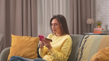Kadın evde boş vakit geçiriyor. Genç bir kadın gününü evinde, oturma odasındaki koltukta oturarak, akıllı telefonunda kart numarası yazarak, internetten alışveriş yaparak, sürpriz satış teklifi alarak, mutlu bir ifadeyle geçiriyor..