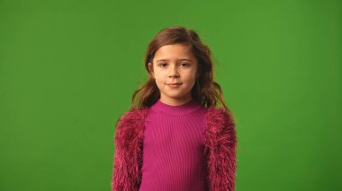 Çocuk duyguları konsepti. Tişörtlü küçük kız kameraya bakıyor, gülümsüyor, krom anahtar yeşil ekranda izole edilmiş arka plan modeli..