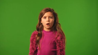 Çocuk duyguları konsepti. Gülümseyen kız etrafa şaşkın bir şekilde bakıyor. Şaşırmış yüz ifadesi, krom anahtar yeşil ekranda izole edilmiş arka plan modeliyle..