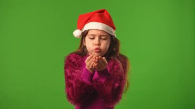 Çocuk duyguları konsepti. Noel Baba şapkalı gülümseyen kız elleri ve gülücükler saçıyor, olumlu ifade, krom anahtar yeşil ekranda izole edilmiş arka plan modeli..