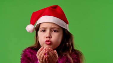 Çocuk duyguları konsepti. Noel Baba şapkalı gülümseyen kız elleri ve gülücükler saçıyor, olumlu ifade, krom anahtar yeşil ekranda izole edilmiş arka plan modeli..